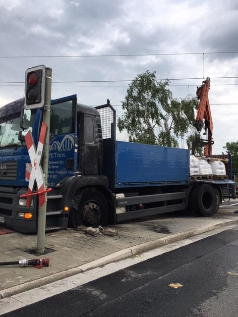 LKW stößt gegen Strommast an einem Bahnübergang.