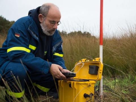 Helfer im THW beobachtet den Wasserstand mit einem mobilen Hochwasserpegel.