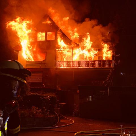 Ein Haus steht in Flammen, die Feuerwehr ist im Einsatz.