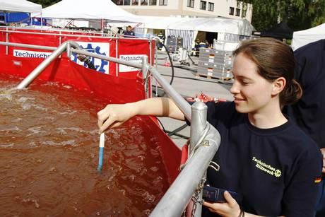 ine THW-Helferin hält ein blaues Stäbchen in ein rotes, mit Wasser gefülltes...