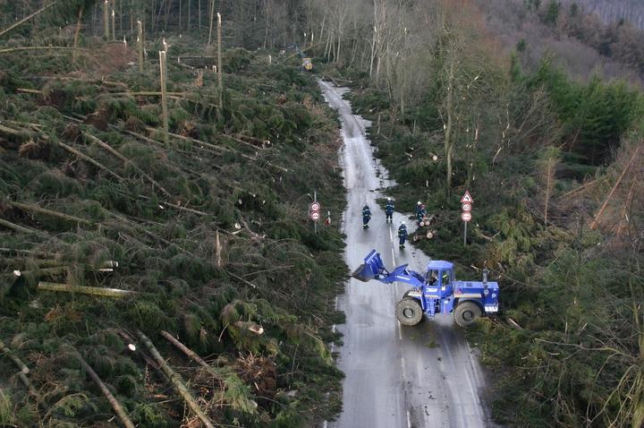 THW-Einsatzkräfte räumen mithilfe eines Baggers eine stark betroffene Straße...